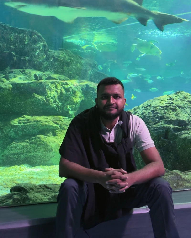 Shameem sitting in front of a large aquarium tank